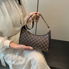 Person holding a patterned handbag with a neutral background