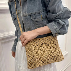 Person holding a beige woven handbag with a denim jacket and white dress.