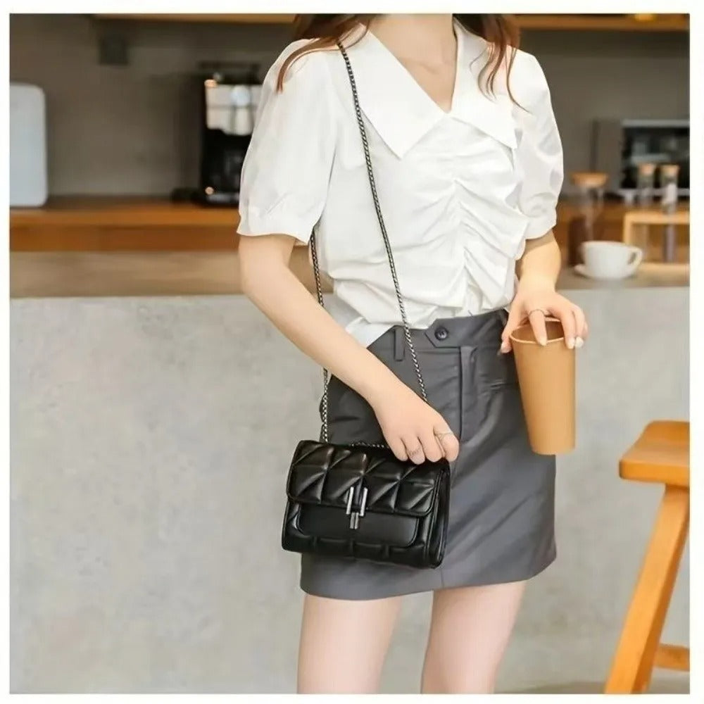 Woman holding a black handbag and a brown cup in a kitchen setting