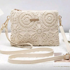 An off-white crocheted clutch bag with a matching shoulder strap, displayed on a white textured surface with a neutral background.