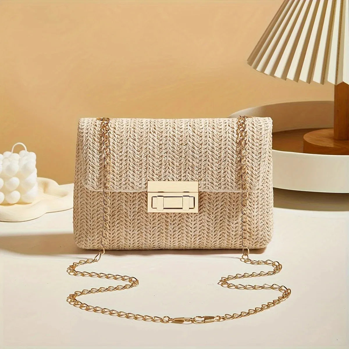 Beige woven handbag with a gold chain strap on a neutral background