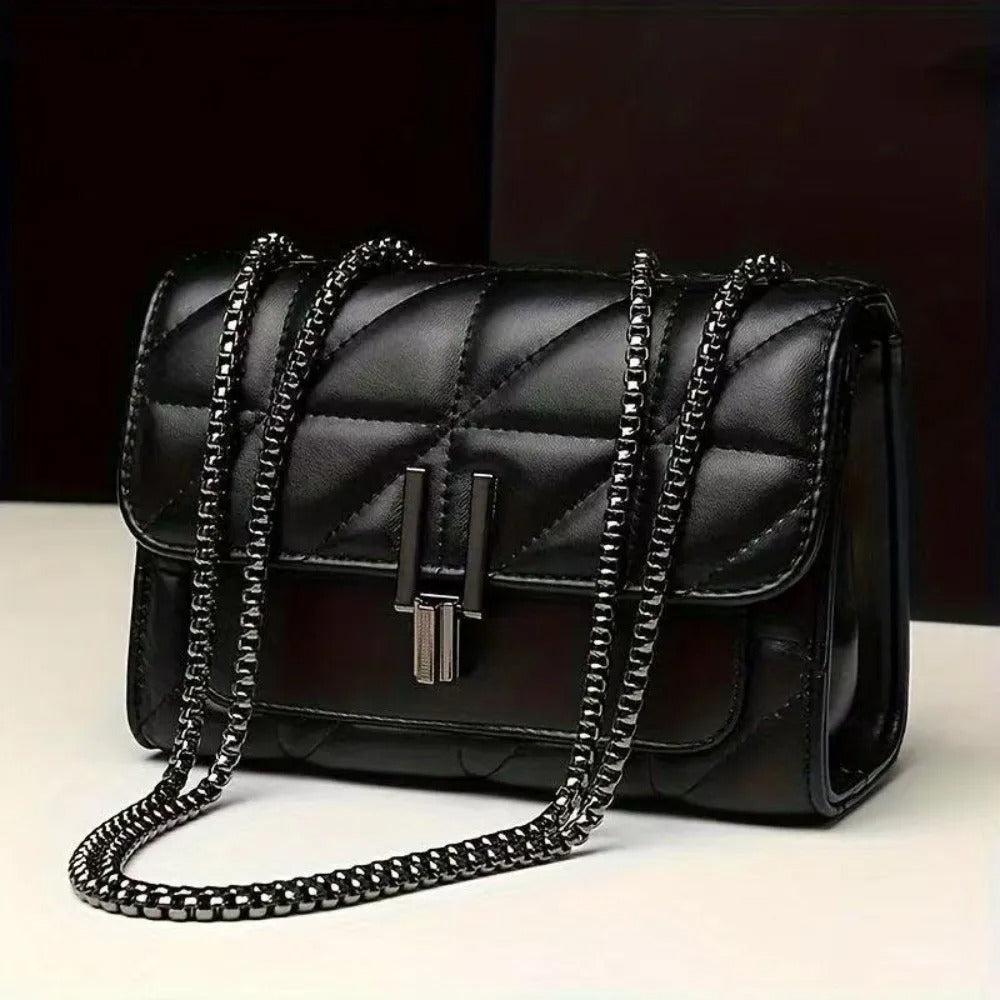 Black quilted handbag with chain strap on a white surface