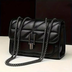 Black quilted handbag with chain strap on a white surface